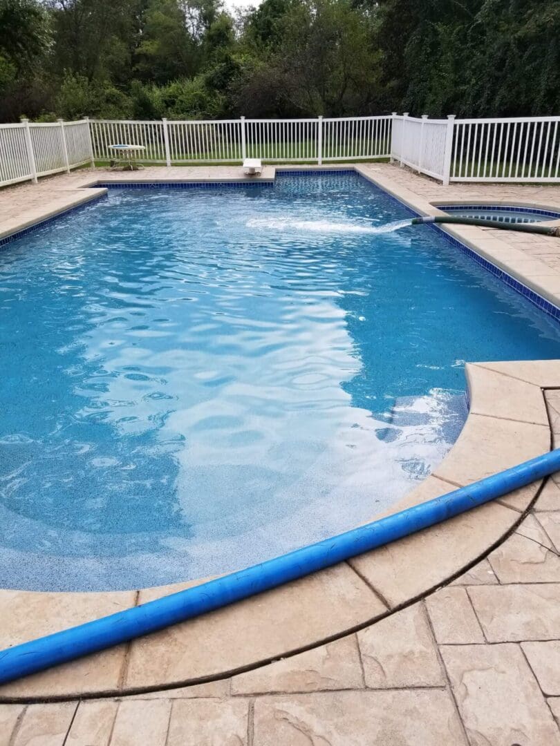 A pool with a fence and a diving board.