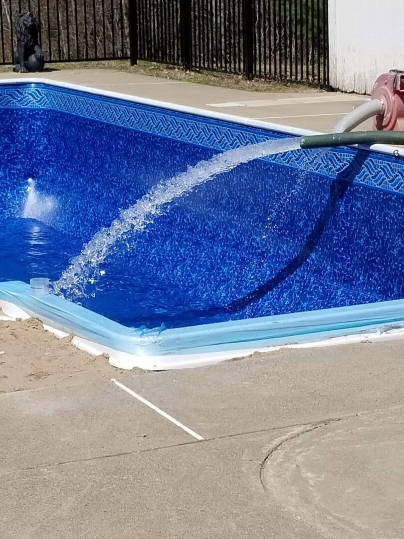 A person is cleaning the pool with a hose.