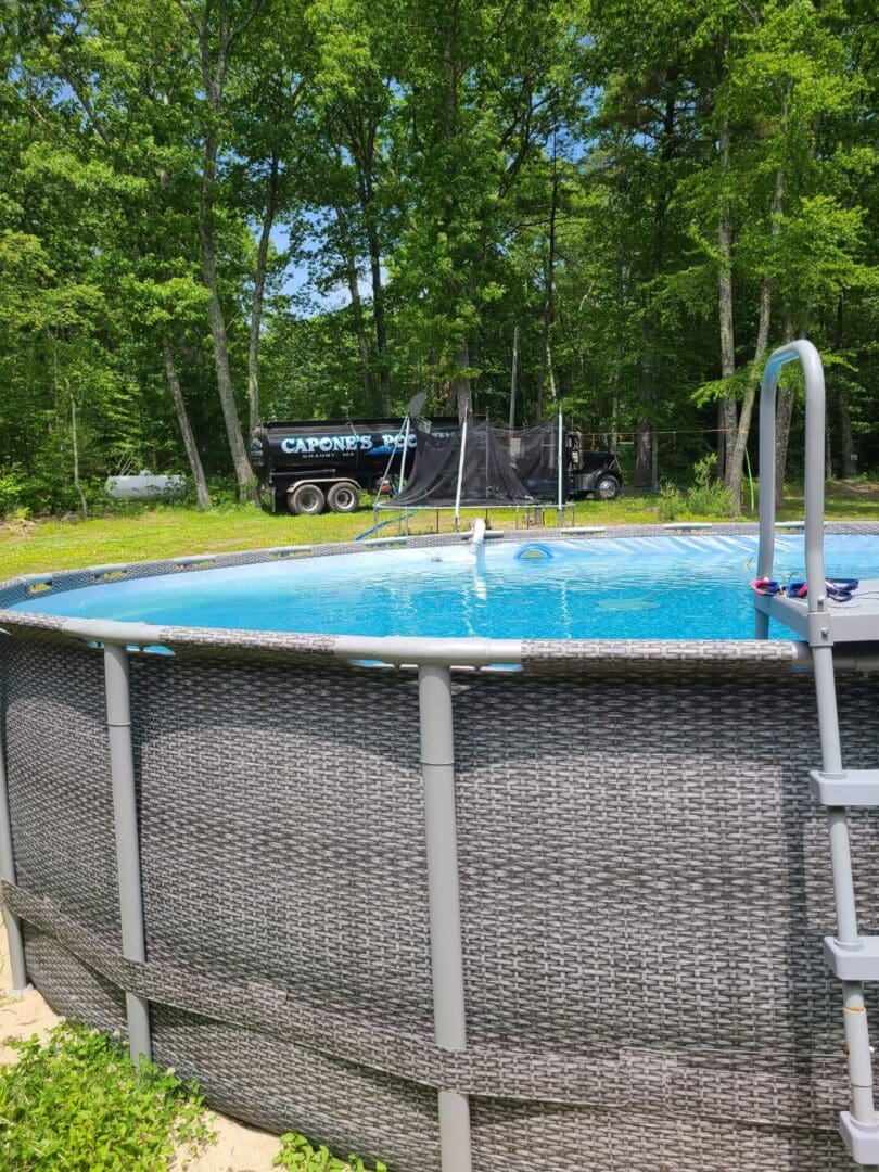 A pool with a ladder and a truck in the background.